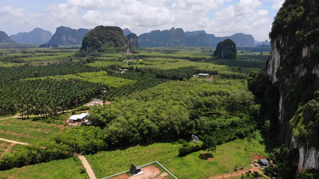 An aerial perspective of a serene valley nestled between towering mountains, adorned with vibrant trees and natural landscapes.