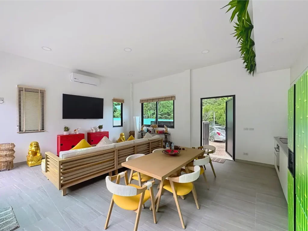 Spacious living and dining area of a Krabi Cliff Villa 2 bedroom villa with wall mounted TV, 6 seat dining table, yellow accent chairs, and garden access