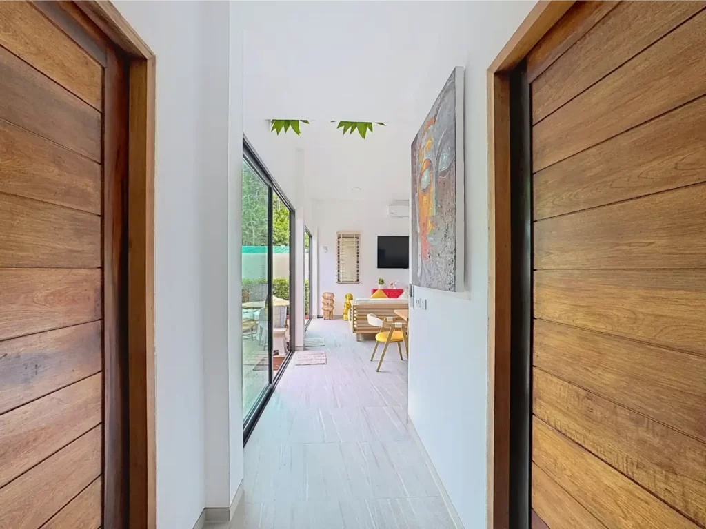 Interior hallway of a Krabi Cliff Villa 2 bedroom villa with hardwood doors, tiled floors, and view through to the open plan living area and pool terrace