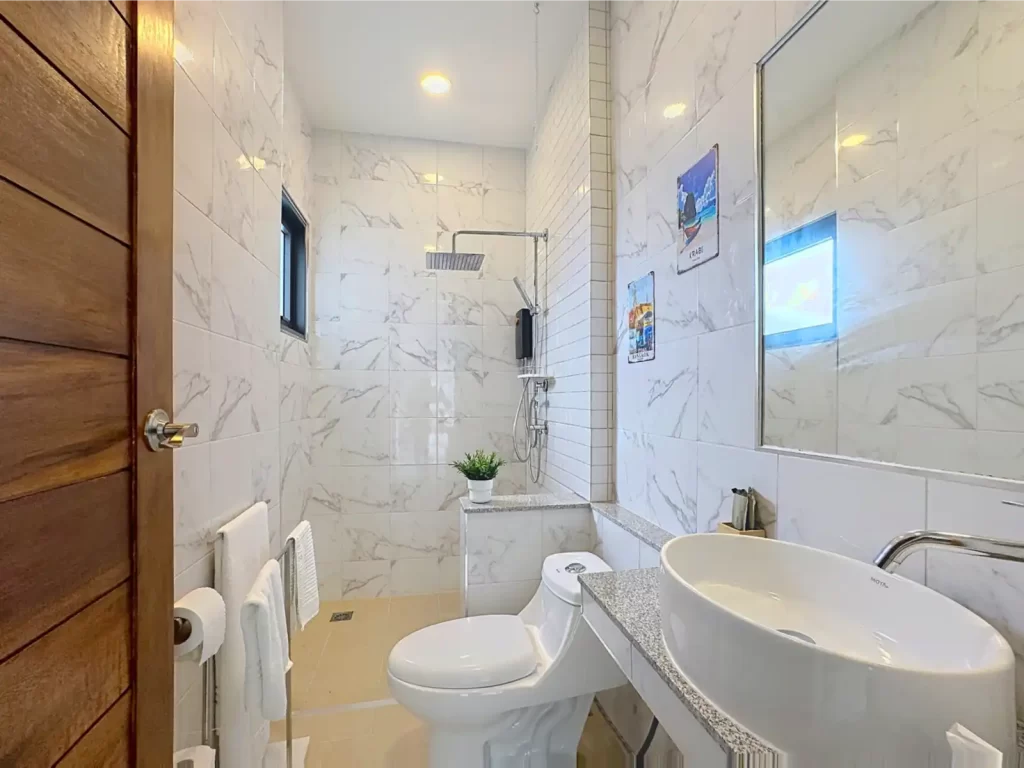 Main bathroom in a Krabi Cliff Villa 2 bedroom villa with marble effect wall tiles, vessel sink, WC, and rainfall shower