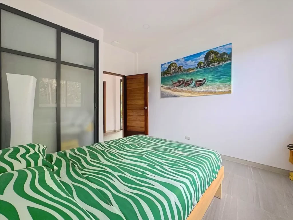 Second bedroom of a Krabi Cliff Villa 2 bedroom villa with double bed, floor to ceiling frosted glass built in wardrobe, and Krabi inspired wall painting