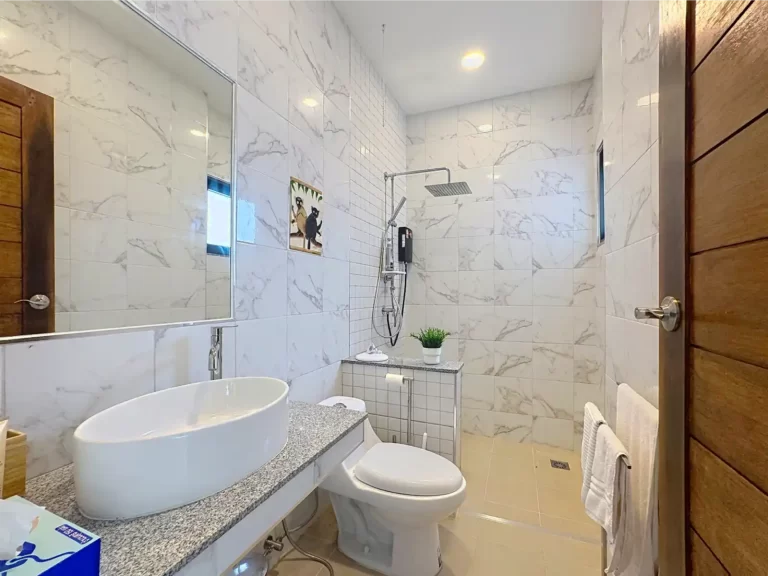 En-suite bathroom of a Krabi Cliff Villa 2 bedroom villa with large vessel sink, granite countertop, WC, rainfall shower, and full height marble effect tiles
