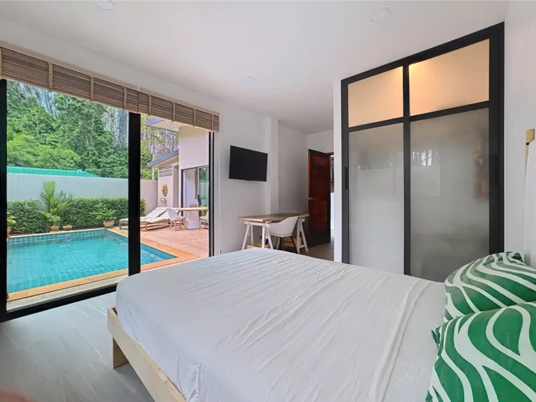 Main bedroom of a Krabi Cliff Villa 2 bedroom villa with direct pool access via sliding doors, wall mounted TV, frosted glass wardrobe, and tropical garden views