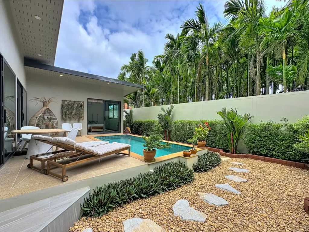 Landscaped garden and private pool of a Krabi Cliff Villa 2 bedroom villa with sun loungers, outdoor dining, pebble pathway, and tall palm trees